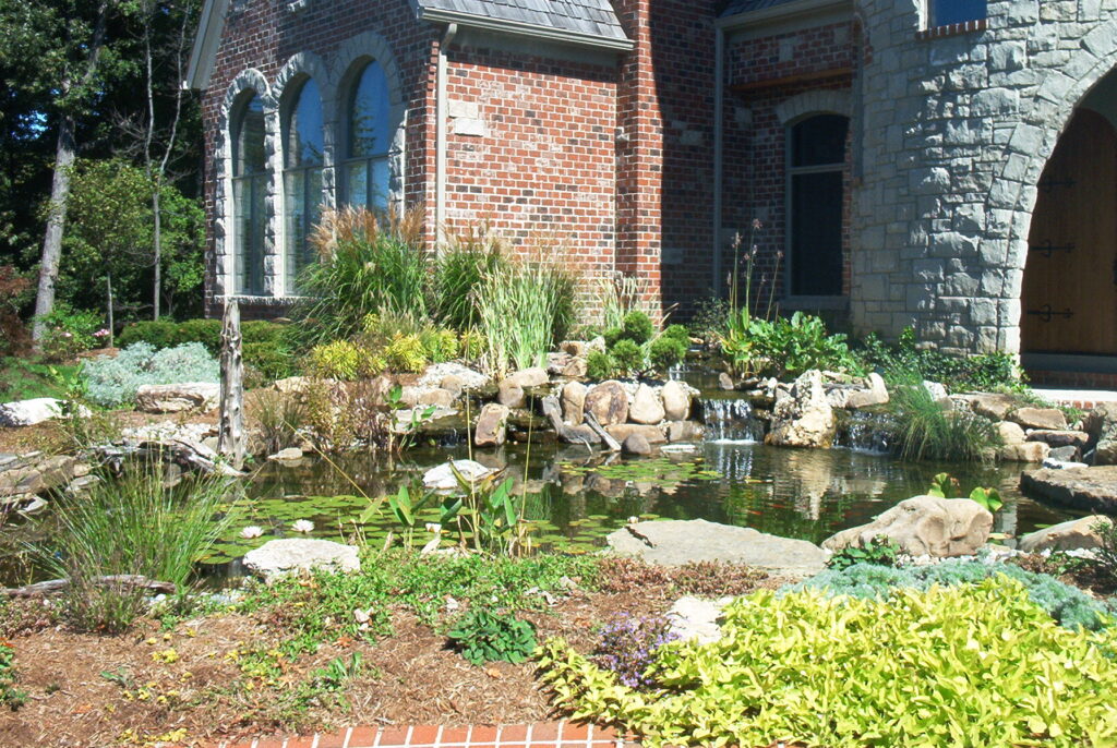 Landscaped backyard koi pond beside a home